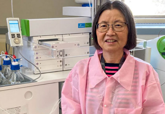 A scientist in a pink lab coat in her lab.